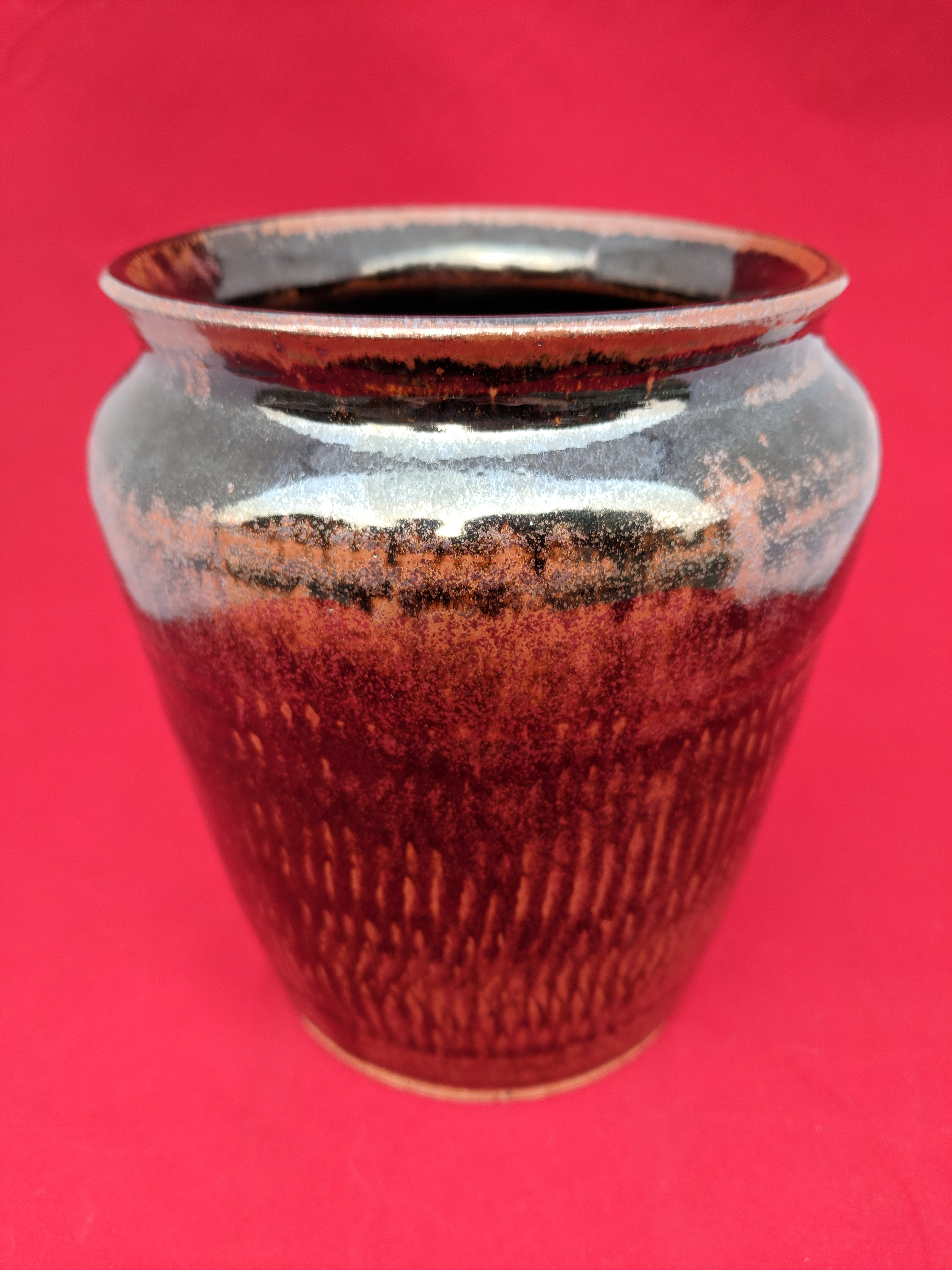 Black and gold textured pottery vase on red background